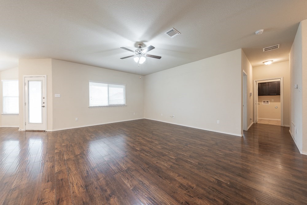 an empty living room with wood floors and a ceiling fan