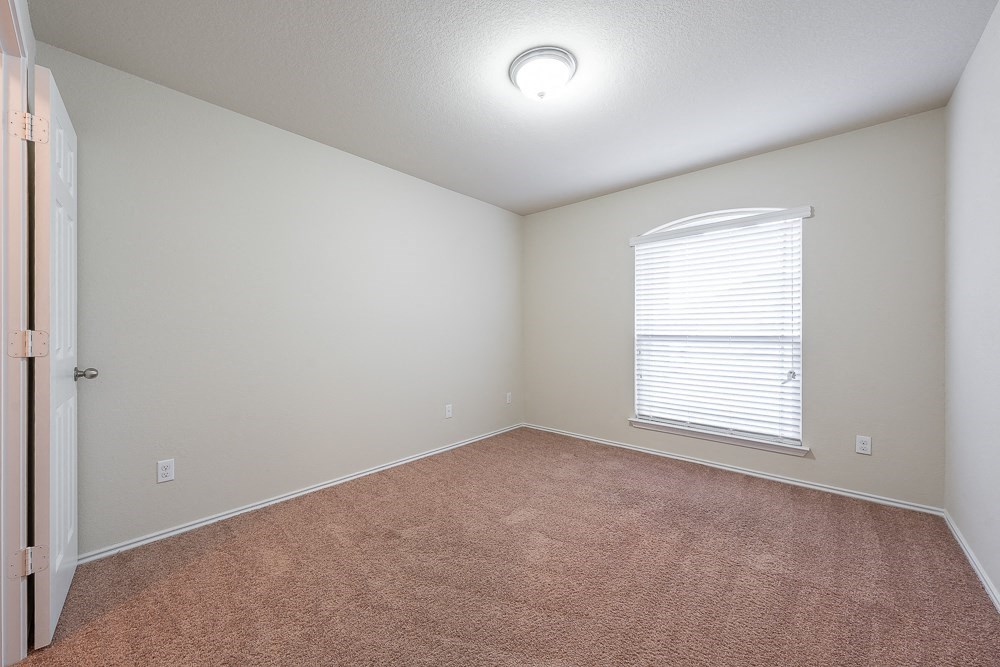 an empty living room with a large window and carpet
