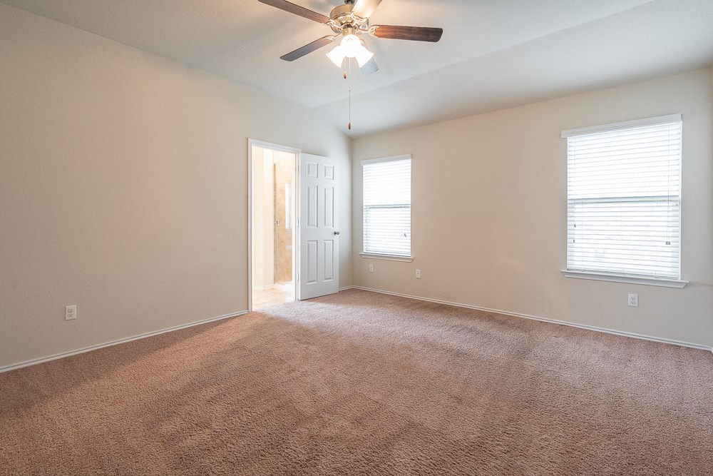 an empty living room with carpet and a ceiling fan