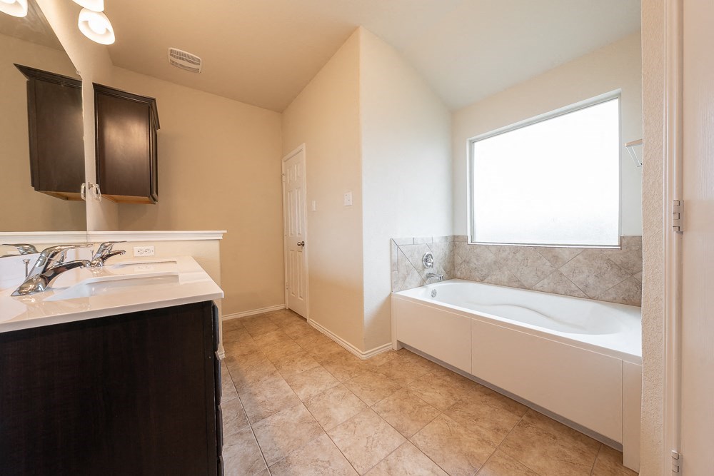 a bathroom with a tub and a sink and a window