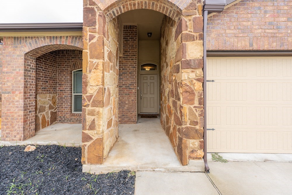 the front door of a brick house with a white garage door