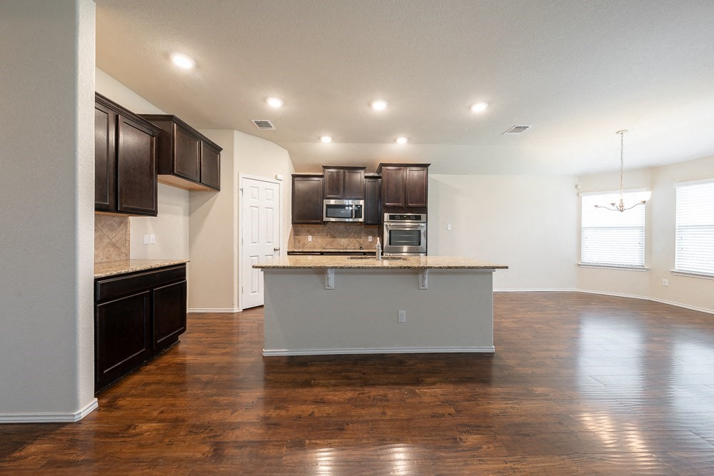 an empty kitchen and living room with wood flooring