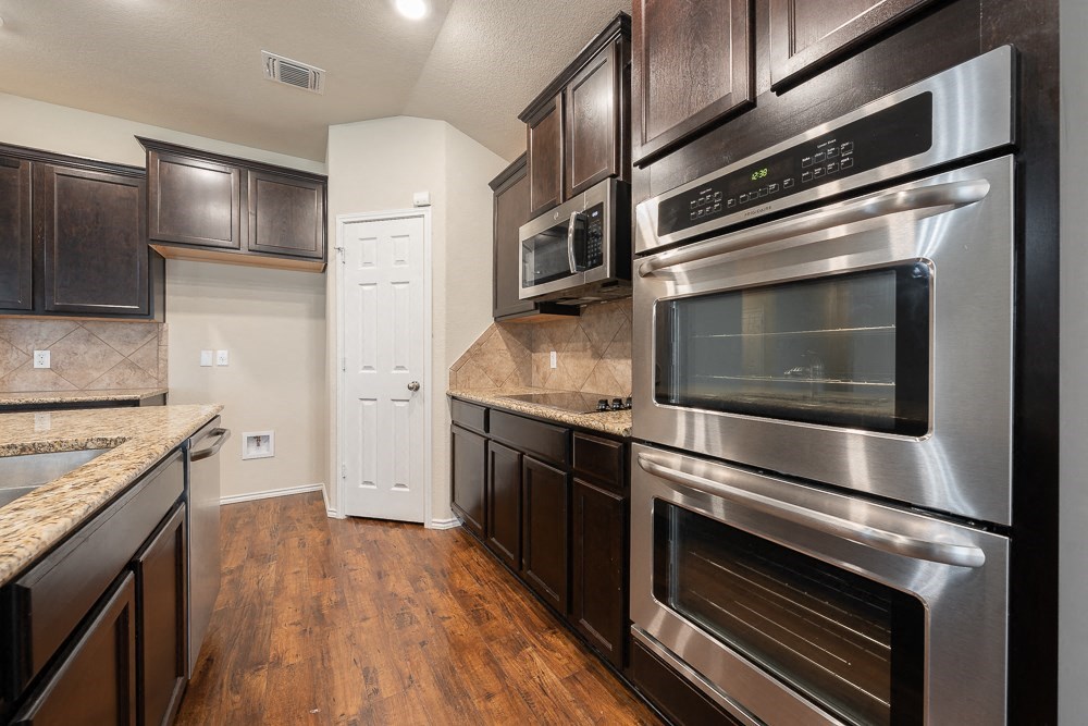 a kitchen with stainless steel appliances and dark wood cabinets