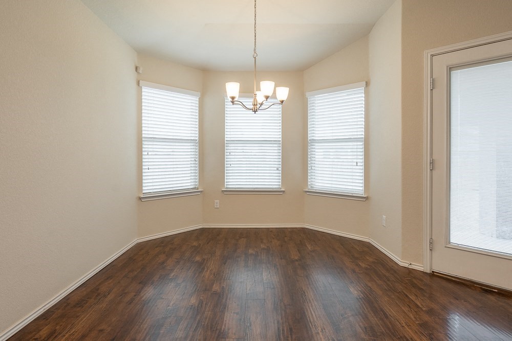 an empty living room with wood flooring and three windows