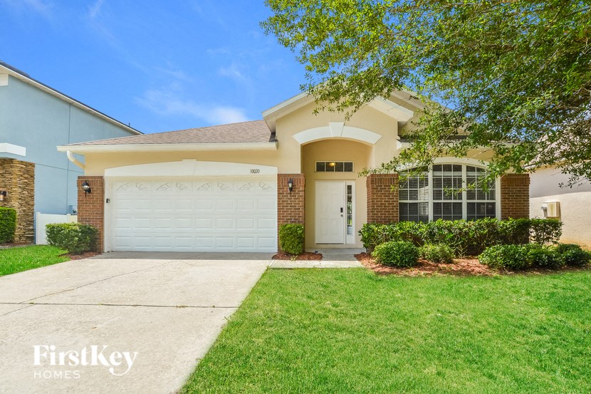 A house with a white garage door and a brown brick wall.
