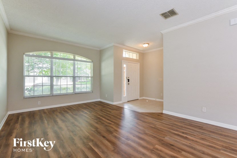 A room with wooden floors and a window with blinds.