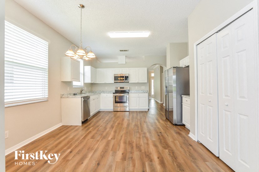 A kitchen with white cabinets and a wooden floor.