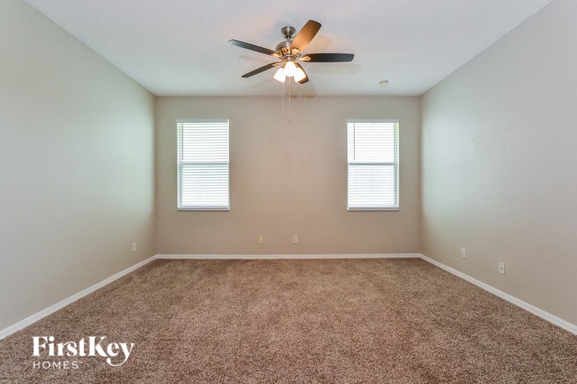 A room with a carpet floor and a ceiling fan.