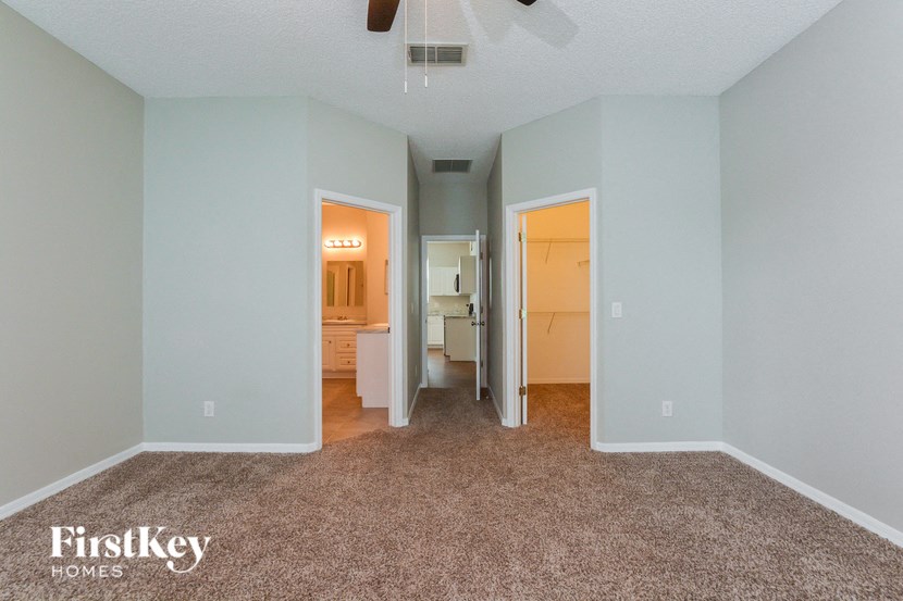 A room with a carpet floor and a ceiling fan.