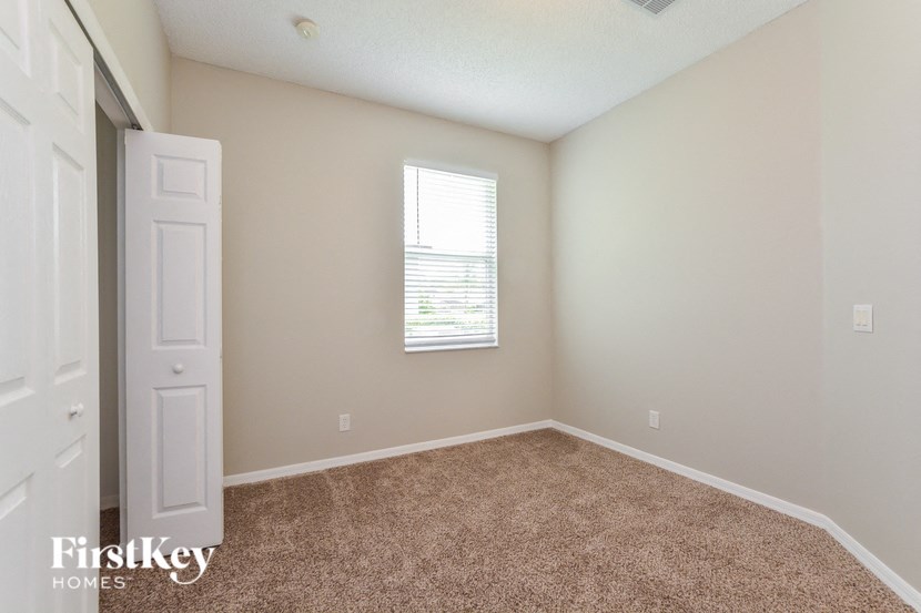 A room with a carpeted floor and a window with blinds.