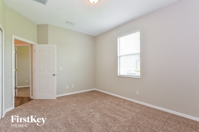 A room with a carpeted floor and a window with blinds.