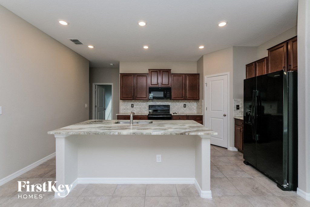 a kitchen with a marble counter top and a black refrigerator