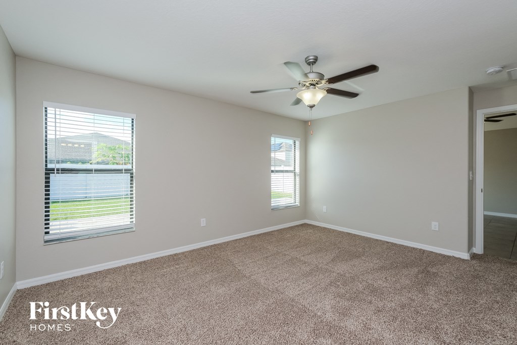 an empty living room with a ceiling fan and a window