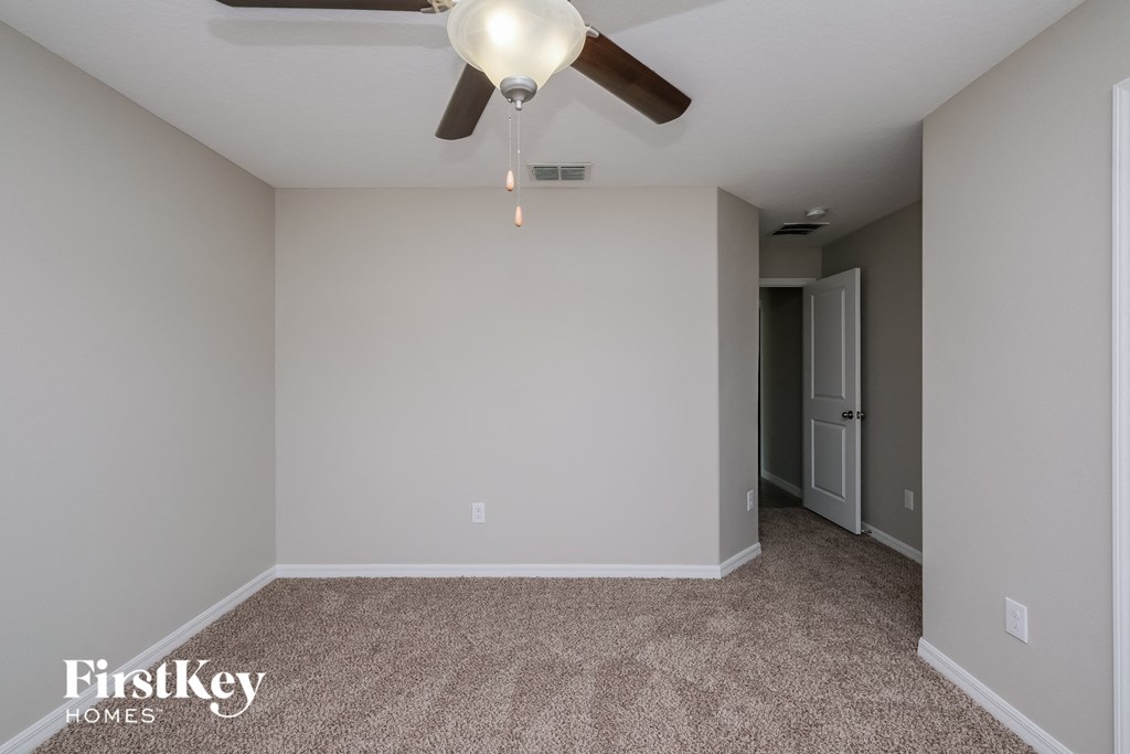 a empty room with a ceiling fan and a white wall