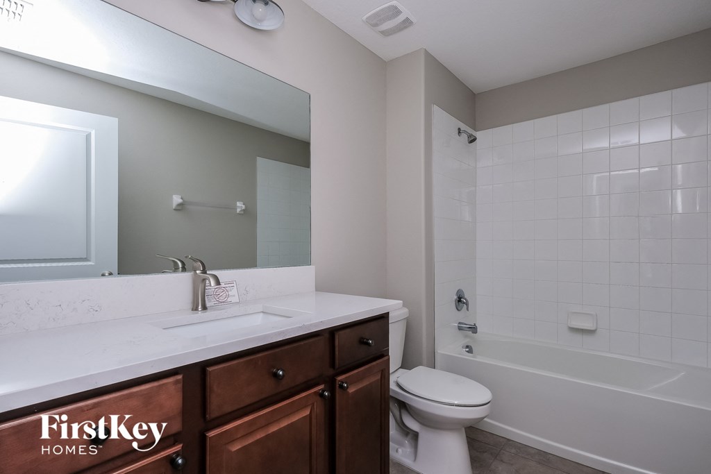 a bathroom with a toilet sink and shower and a mirror