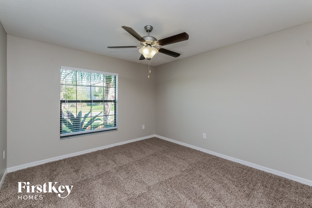 an empty living room with a ceiling fan and a window