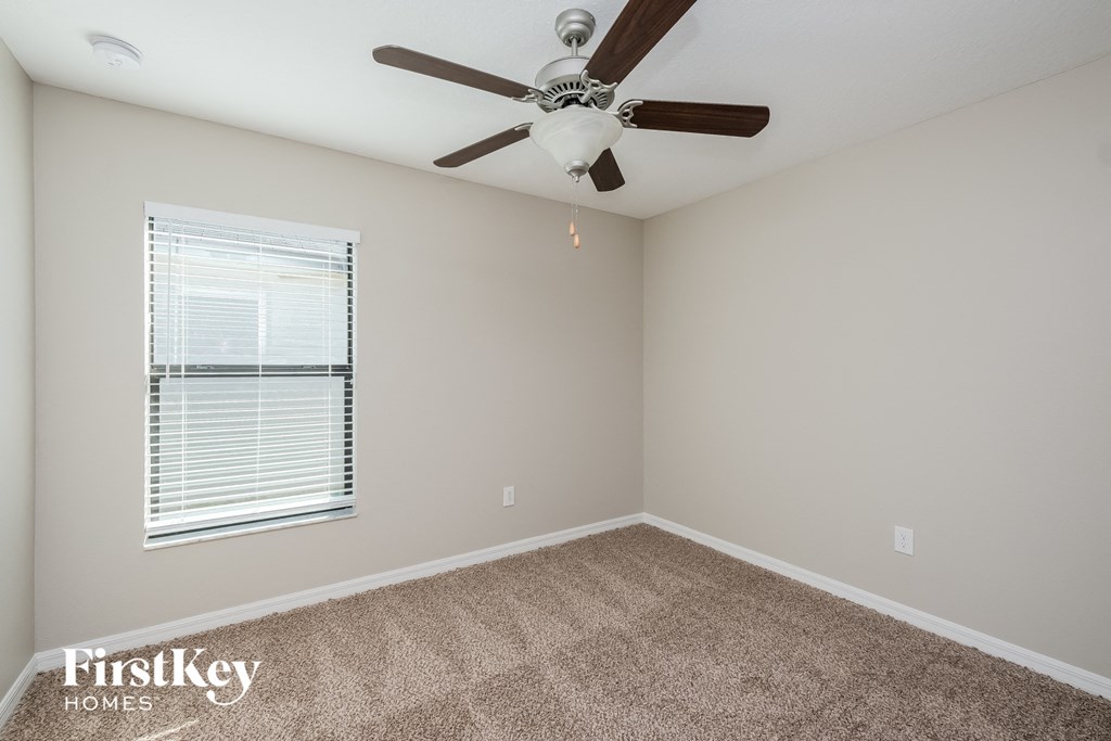 a carpeted room with a ceiling fan and a window
