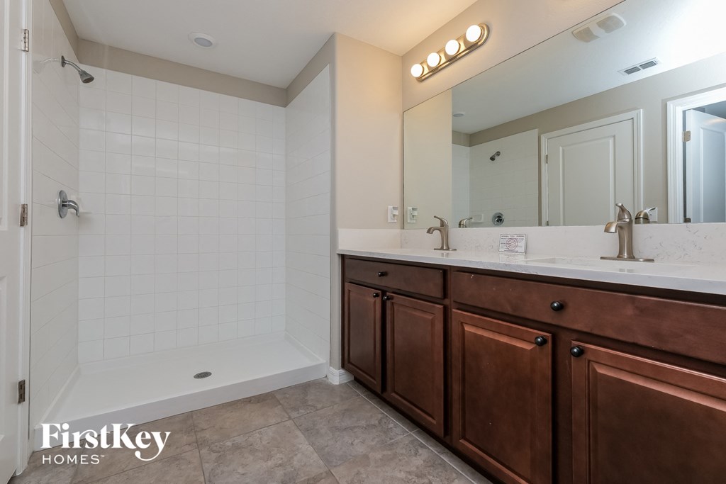 the master bathroom has a large vanity with two sinks and a shower