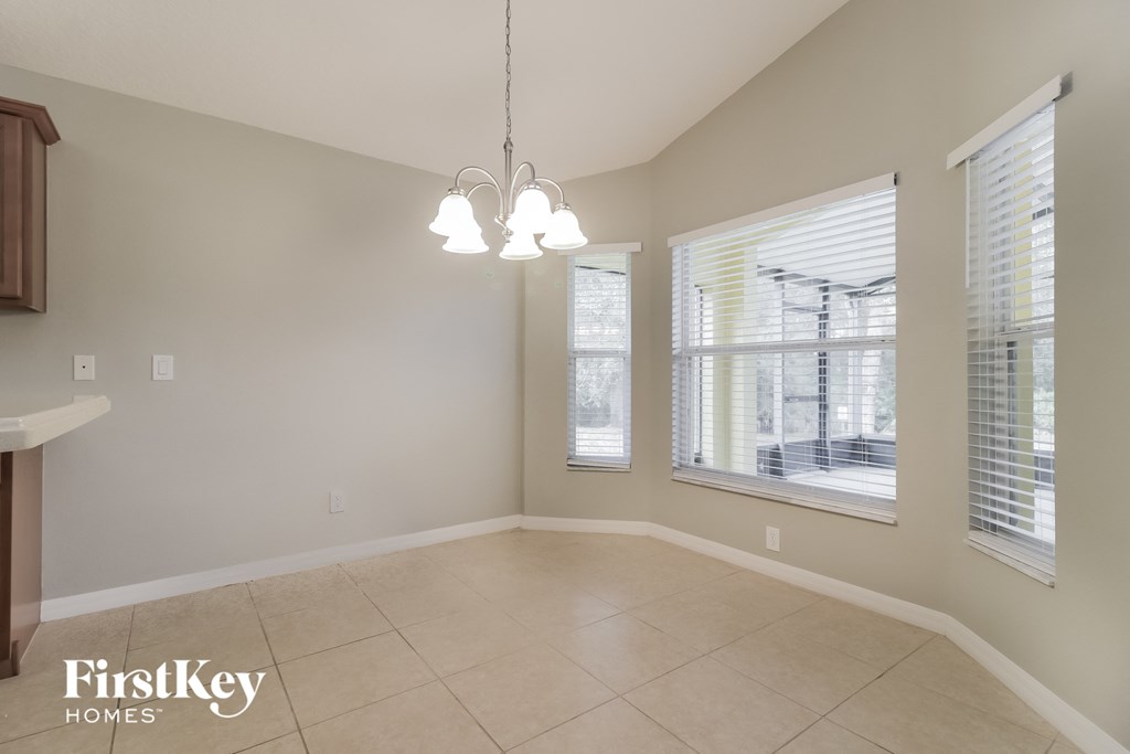 an empty dining room with three windows and a tile floor