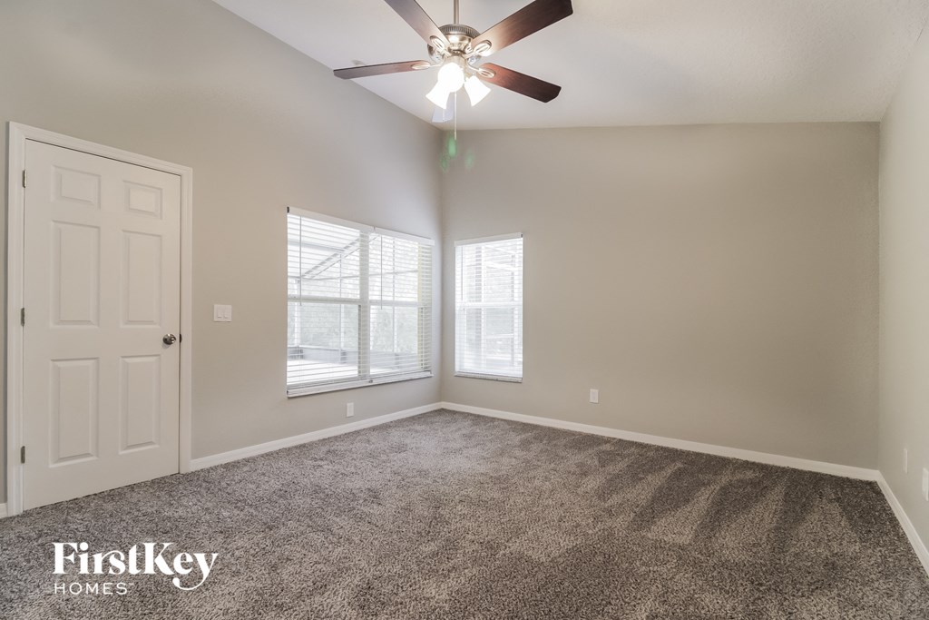 the spacious living room with ceiling fan and window