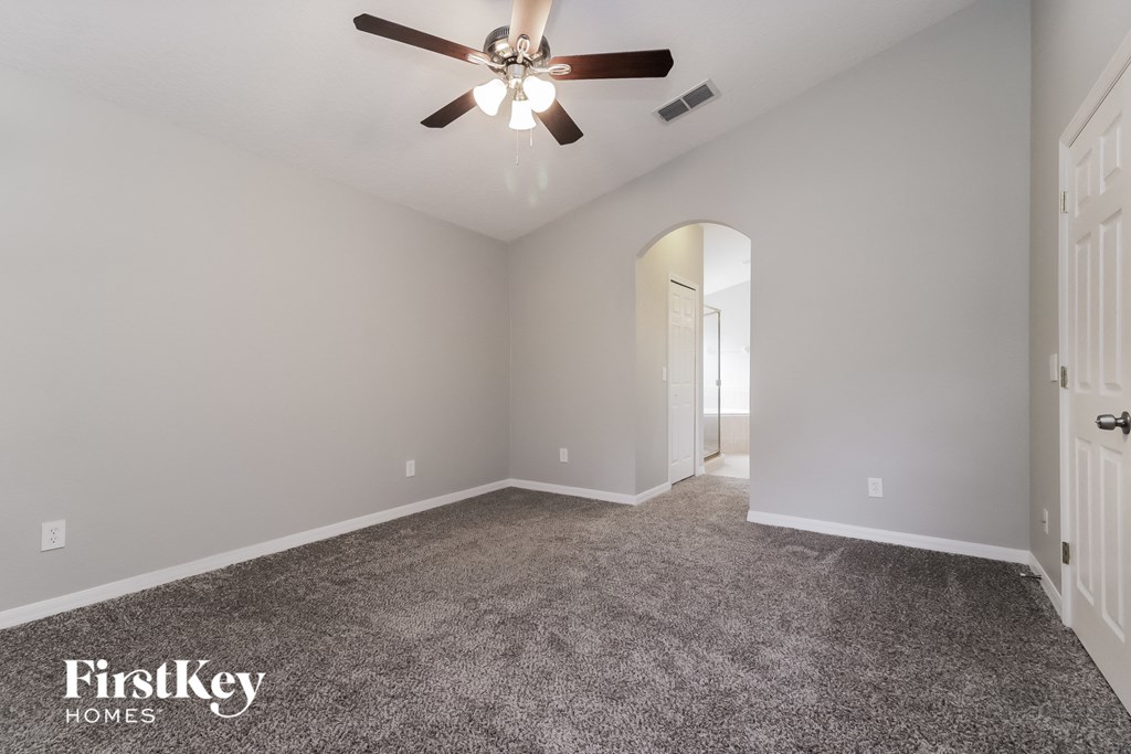 the master bedroom has a carpeted floor and a ceiling fan
