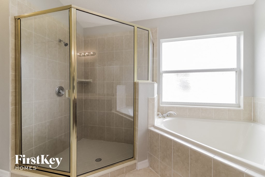 a bathroom with a shower and a tub and a window