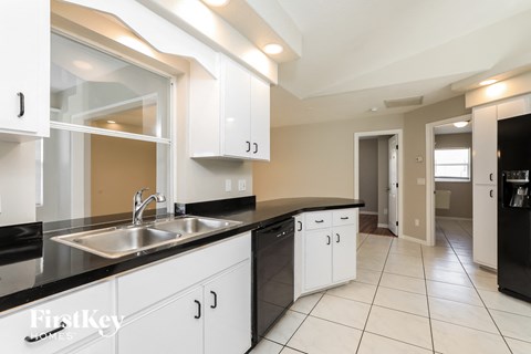 a kitchen with white cabinets and black counter tops and a sink
