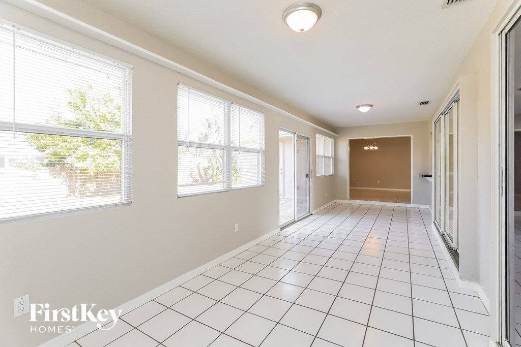 an empty hallway with a white tiled floor and large windows