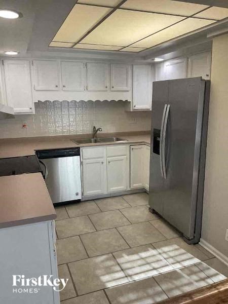 A kitchen with white cabinets and a stainless steel refrigerator.