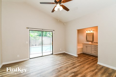 A spacious room with a ceiling fan and sliding glass doors leading to a backyard.