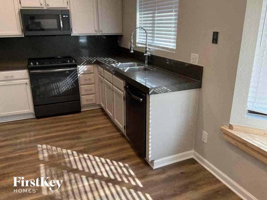 A kitchen with a black countertop and white cabinets.
