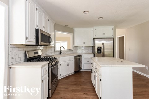 A kitchen with white cabinets and appliances.