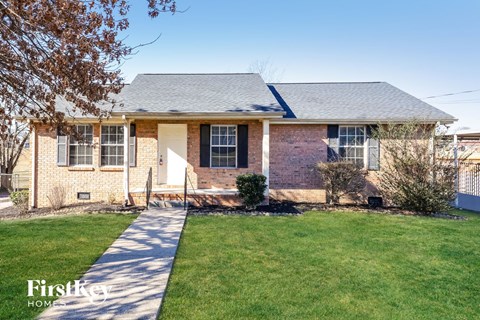 A brick house with a white door and a small front yard.