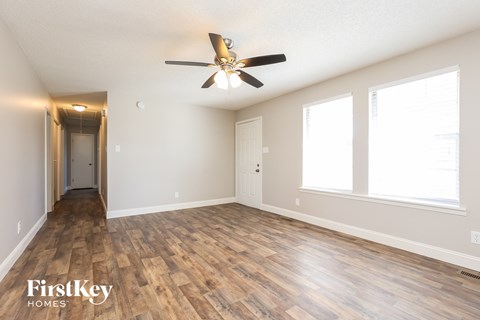 A spacious room with wooden flooring and a ceiling fan.