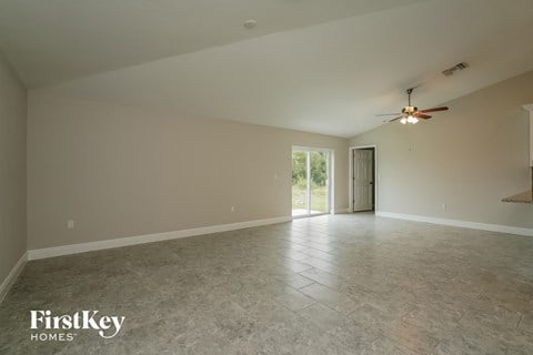 an empty living room with a ceiling fan and tile floor