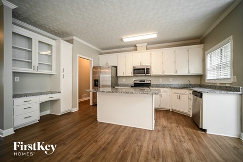 A kitchen with white cabinets and a wooden floor.