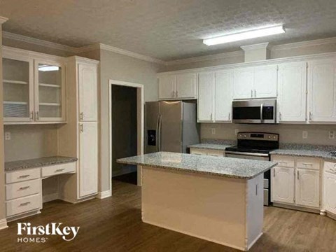A kitchen with white cabinets and a granite countertop.