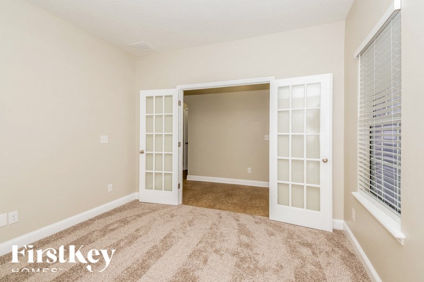 A room with a carpeted floor and a white door with glass panels.