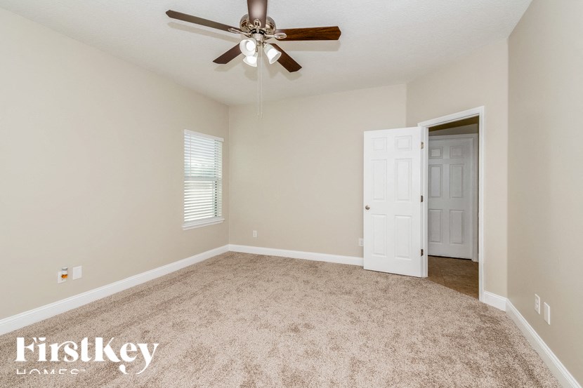A room with a carpeted floor and a ceiling fan.