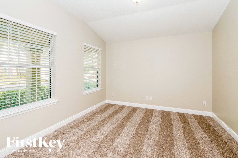 A room with a striped carpet and a window with blinds.