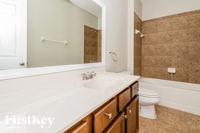 A bathroom with a white sink and brown cabinets.