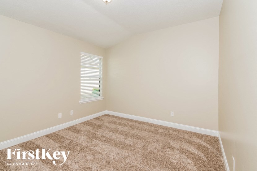 A room with a carpeted floor and a window with blinds.