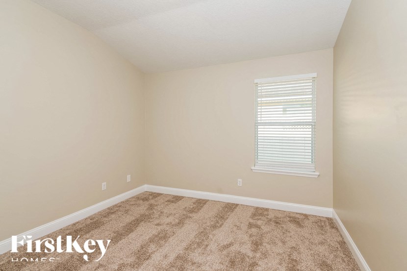 A room with a carpeted floor and a window with blinds.