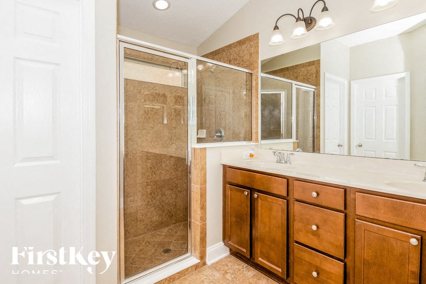 A bathroom with a walk-in shower and double vanity sinks.