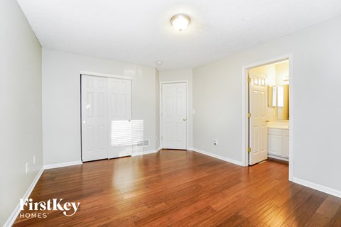 a living room with a hard wood floor and a door to a bathroom