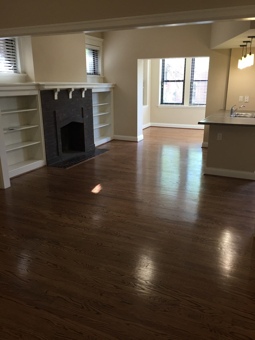 an empty living room with a fireplace and wooden floors