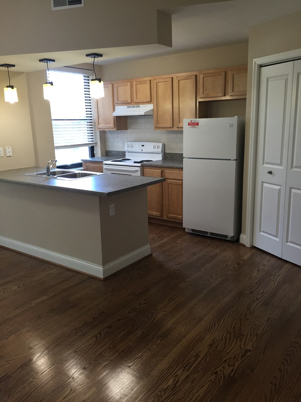 an empty kitchen with wooden floors and a refrigerator