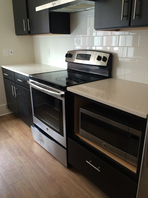 A black stove top oven with a silver handle and a black microwave above it.