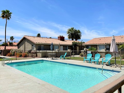 A pool with blue water and chairs around it.
