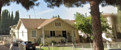 A yellow house with a black car parked in front.